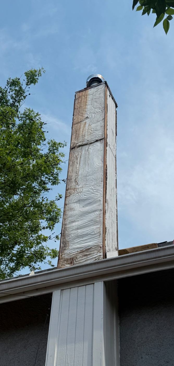 Chimney chase with the siding stripped off showing rotted sheathing and corner boards after years of water getting behind the siding