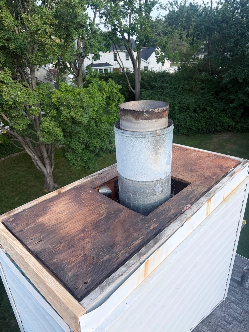 Old chimney chase cover removed showing plywood chase top soaked and rotted through from years of water running onto it