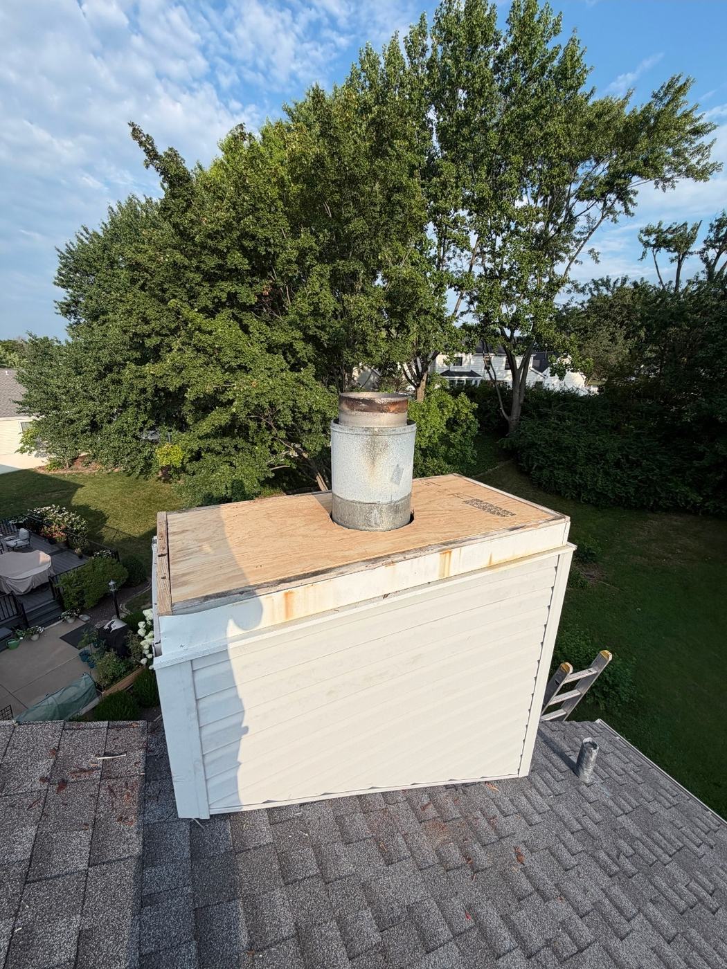 New chimney chase top seen from the roof with clean edges all round so the new cover can overhang past the siding