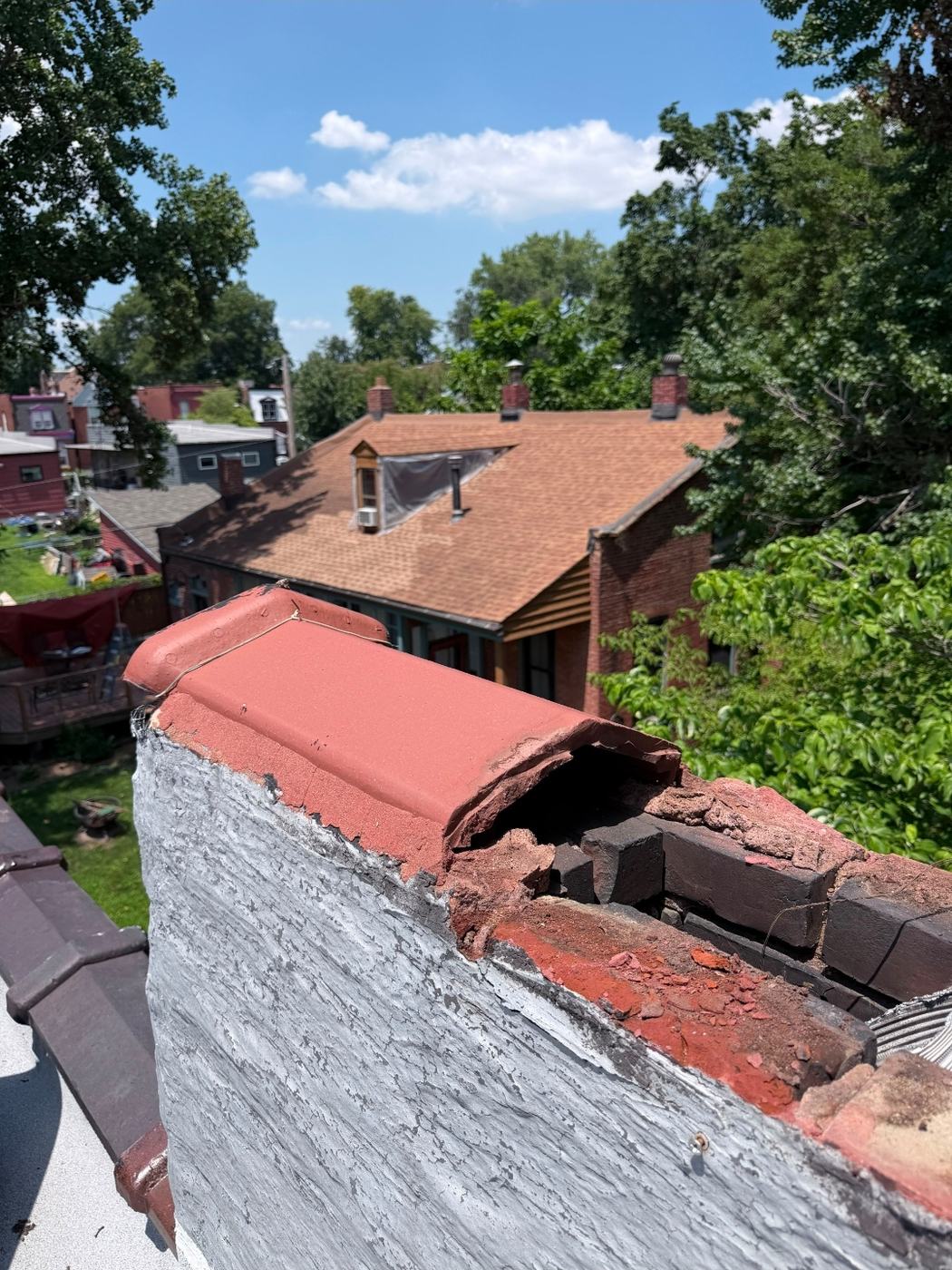 Broken clay coping tile on a chimney with brick and debris exposed underneath, St. Louis MO