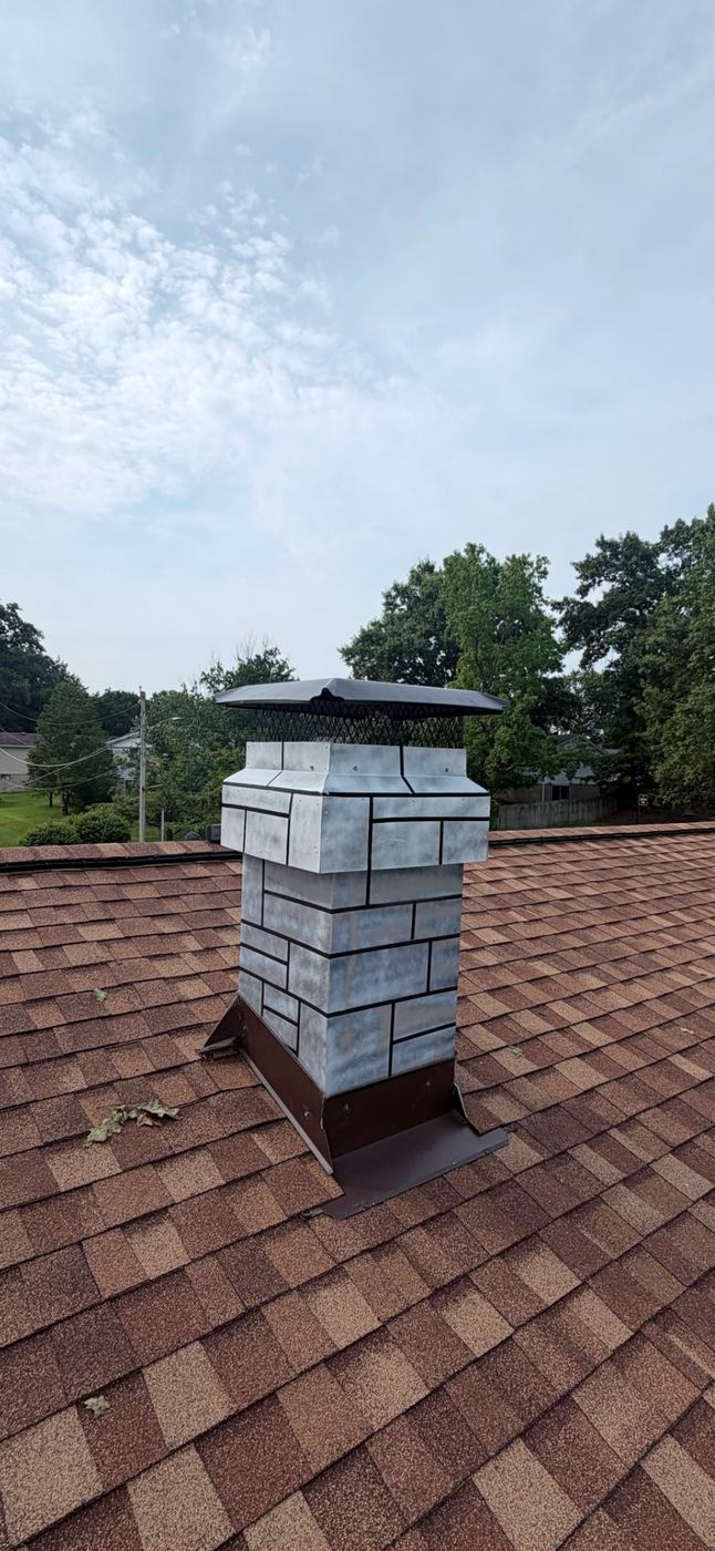 Custom fabricated decorative chimney chase surround in sheet metal pressed with a faux brick pattern, wrapping the metal liner, St. Louis MO