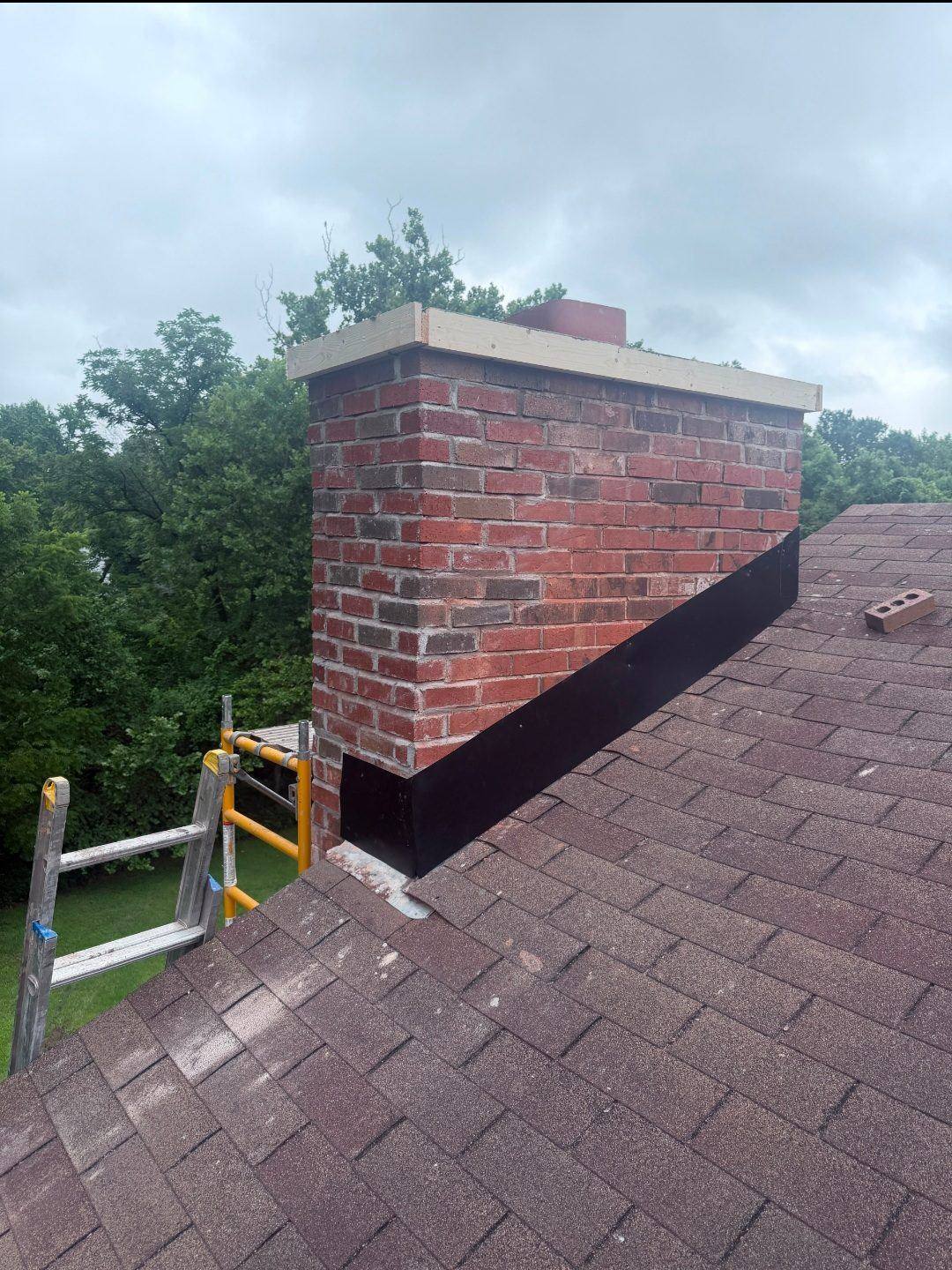 Chimney nearly finished — new brick to top, level board for crown formwork, new flashing at base