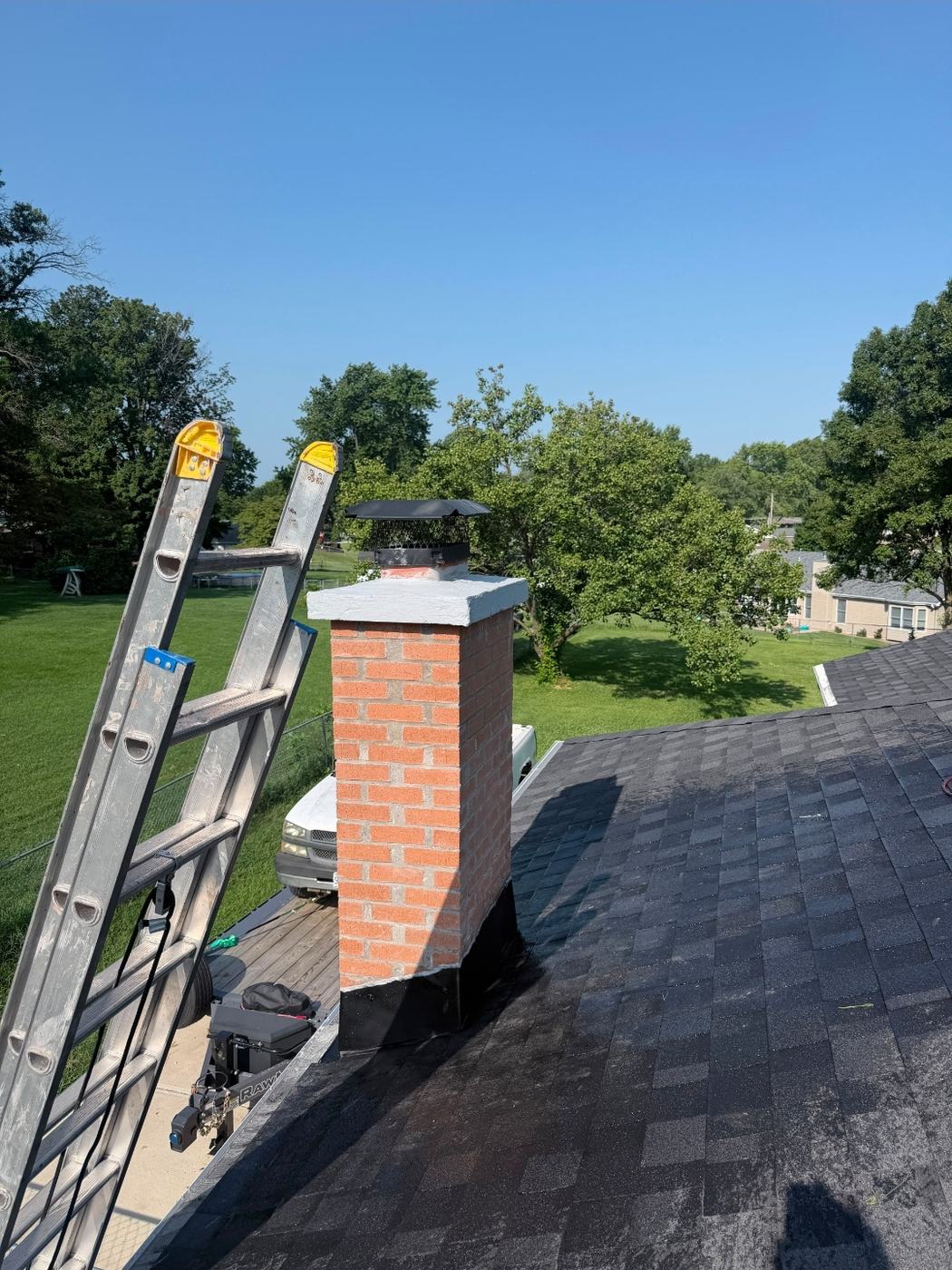 Side view of the finished chimney rebuild with new counterflashing worked into the shingles and the crown overhang standing clear