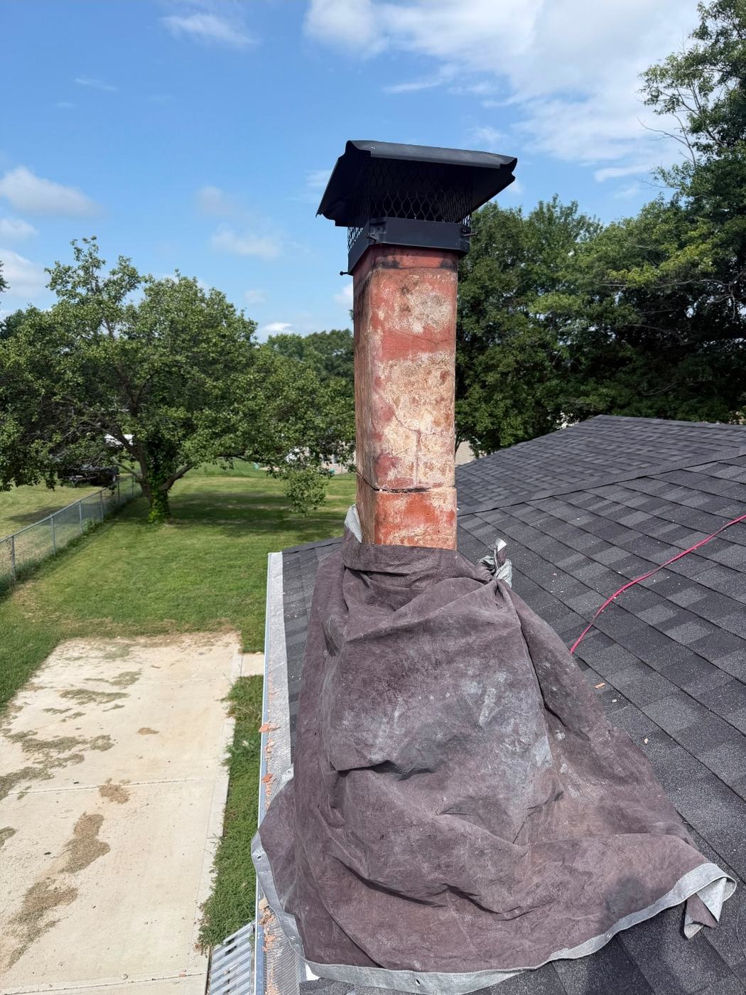 Every brick above the roofline removed with only the clay flue tile left standing and the roof tarped for protection