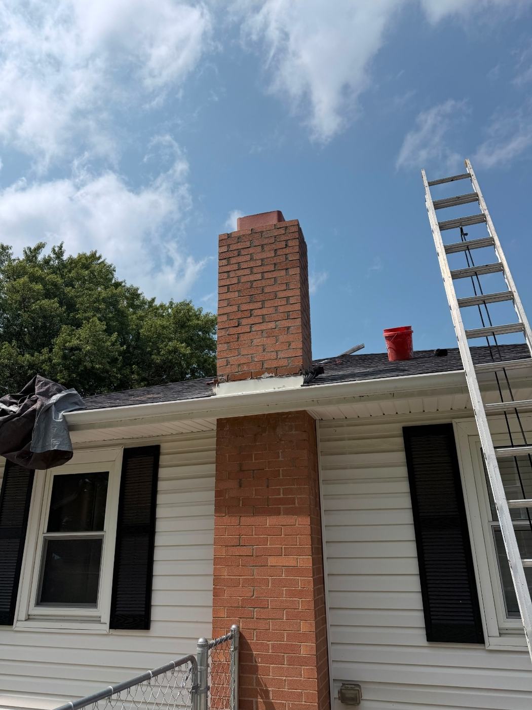 View from the ground of new chimney brick above the roofline meeting the original brick below