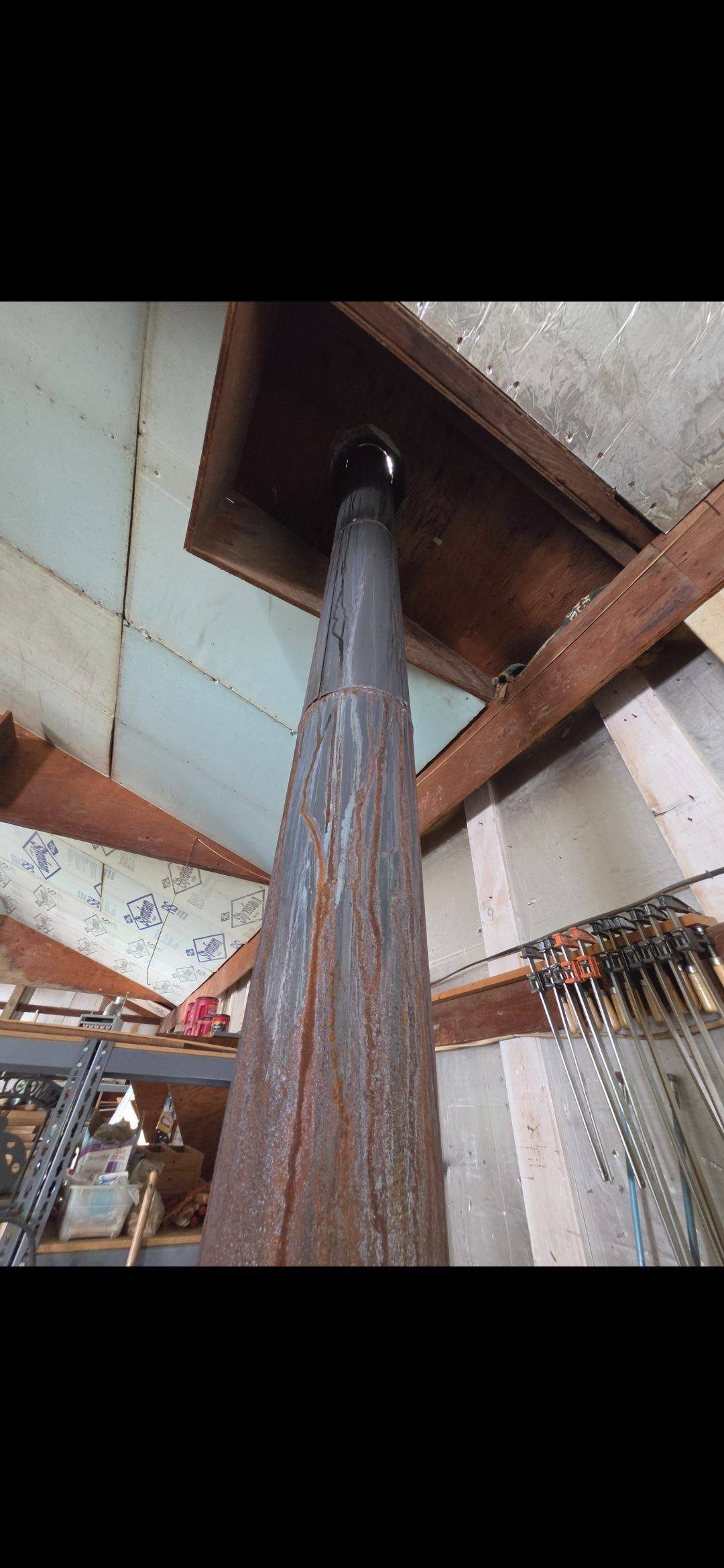Rusted single-wall stove pipe through a wood ceiling
